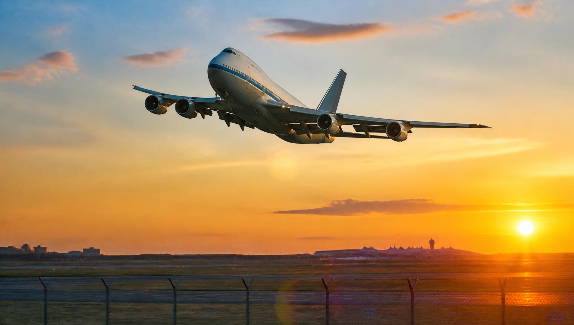 Airliner banking into a glowing sunset on final approach